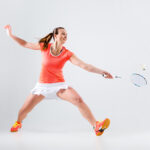 Young woman playing badminton over white background